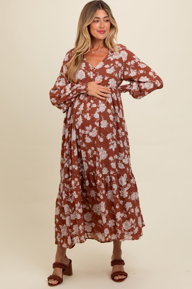 woman wearing a rust floral maternity dress and holding her baby bump