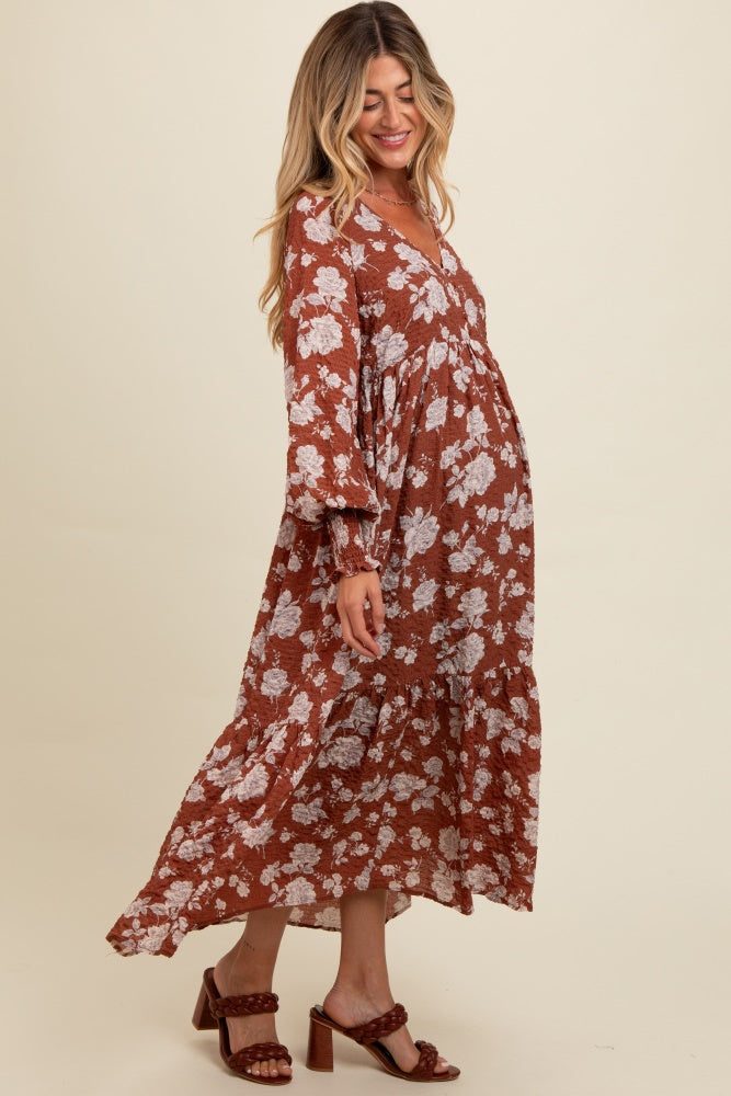 woman wearing a brown floral maternity maxi dress with a ruffled hem and a visible baby bump