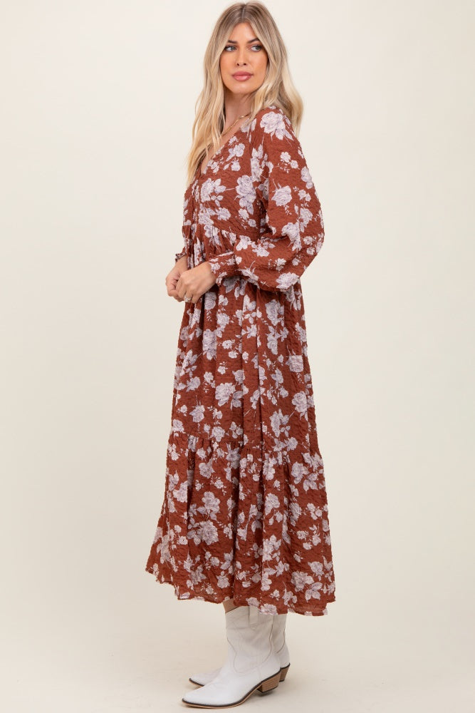 woman wearing a brown floral maxi dress with long sleeves and a flowing skirt, styled with white cowboy boots