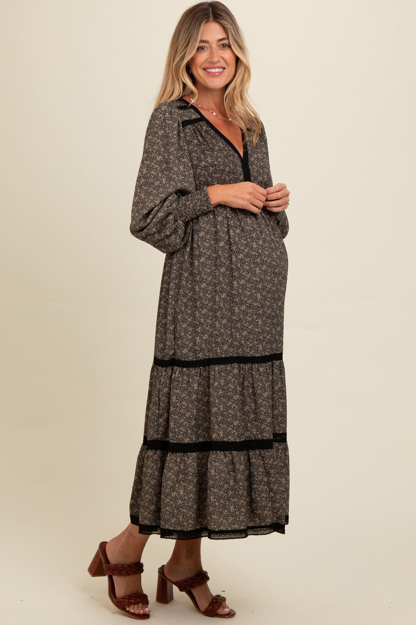 woman wearing a black floral maternity maxi dress with tiered ruffles and long sleeves, showing her baby bump