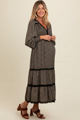 woman wearing a black floral maternity maxi dress with tiered ruffles and long sleeves, showing her baby bump
