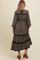 woman wearing a black floral maternity maxi dress with tiered skirt and long sleeves, showing the back view