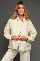woman wearing a cream-colored maternity denim jacket with pockets and button details, holding her baby bump