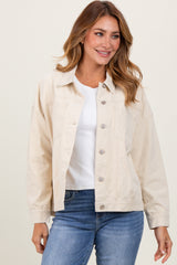 woman wearing a light beige oversized denim jacket with button closure and a white top, paired with blue jeans