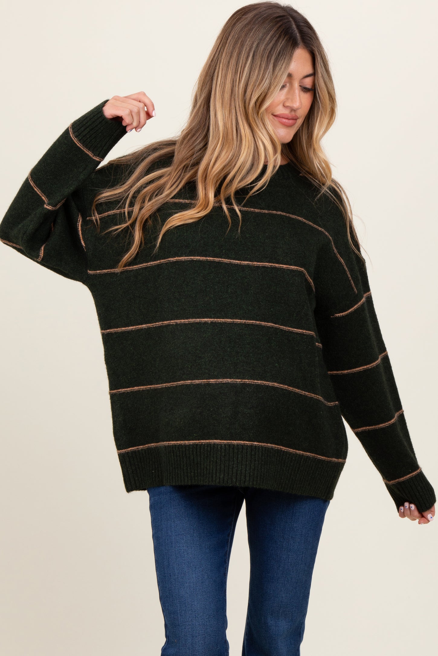 woman wearing a dark green striped oversized maternity sweater with a relaxed fit
