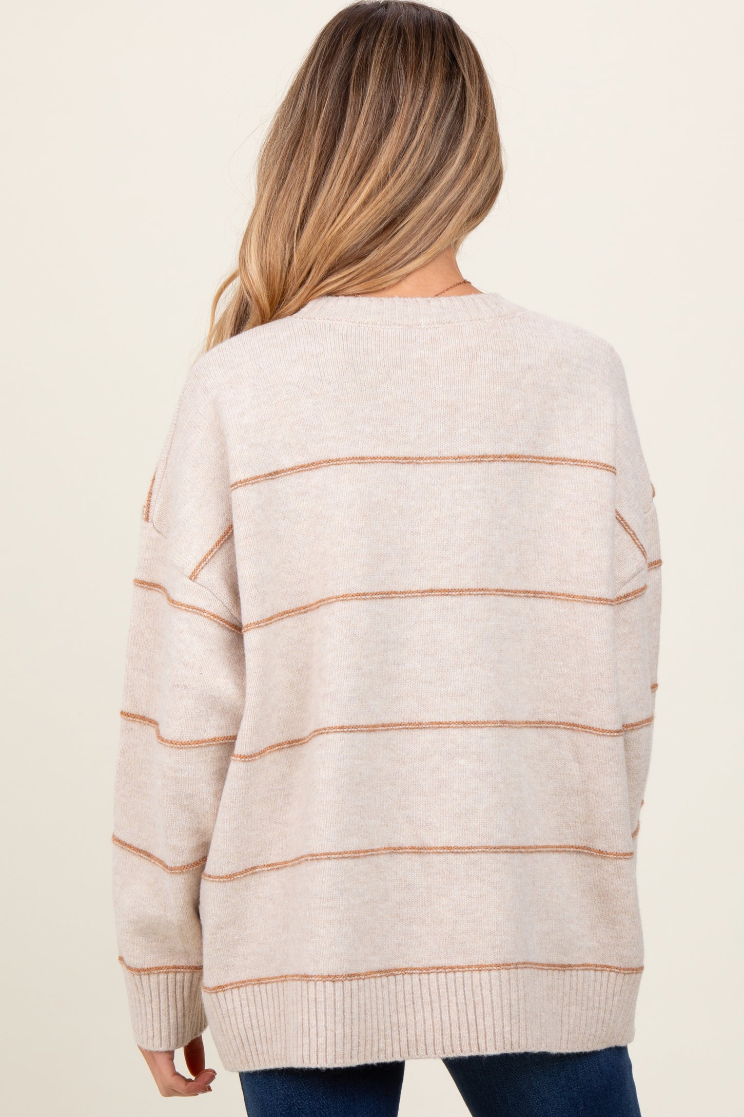 woman wearing a beige maternity sweater with light brown stripes, shown from the back
