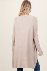 woman wearing a beige long cardigan with a relaxed fit and ribbed detail on the hem, viewed from the back