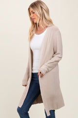 woman wearing a long beige cardigan over a white top and paired with dark jeans
