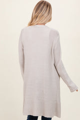 woman wearing a long beige cardigan styled with a relaxed fit, shown from the back