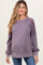 woman wearing a purple maternity sweatshirt with lace detail on sleeves and a visible baby bump