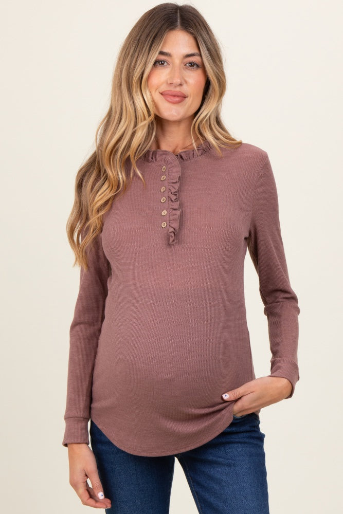 woman wearing a mauve long sleeve maternity top with a ruffle neckline and buttons, showcasing her baby bump