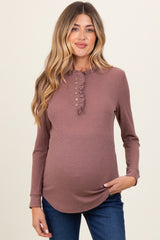 woman wearing a mauve long sleeve maternity top with a ruffle neckline and buttons, showcasing her baby bump