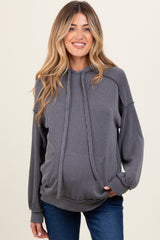 woman wearing a gray ribbed maternity hoodie with a relaxed fit and drawstring detail, smiling at the camera