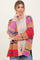 woman wearing a colorful oversized cardigan with pink, orange, and red stripes over a light sweater and jeans