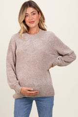 woman wearing a beige knit maternity sweater and holding her baby bump