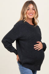 woman wearing a dark gray maternity sweater and holding her baby bump