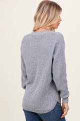 woman wearing a light gray oversized knitted sweater with a relaxed fit and side slits, seen from the back