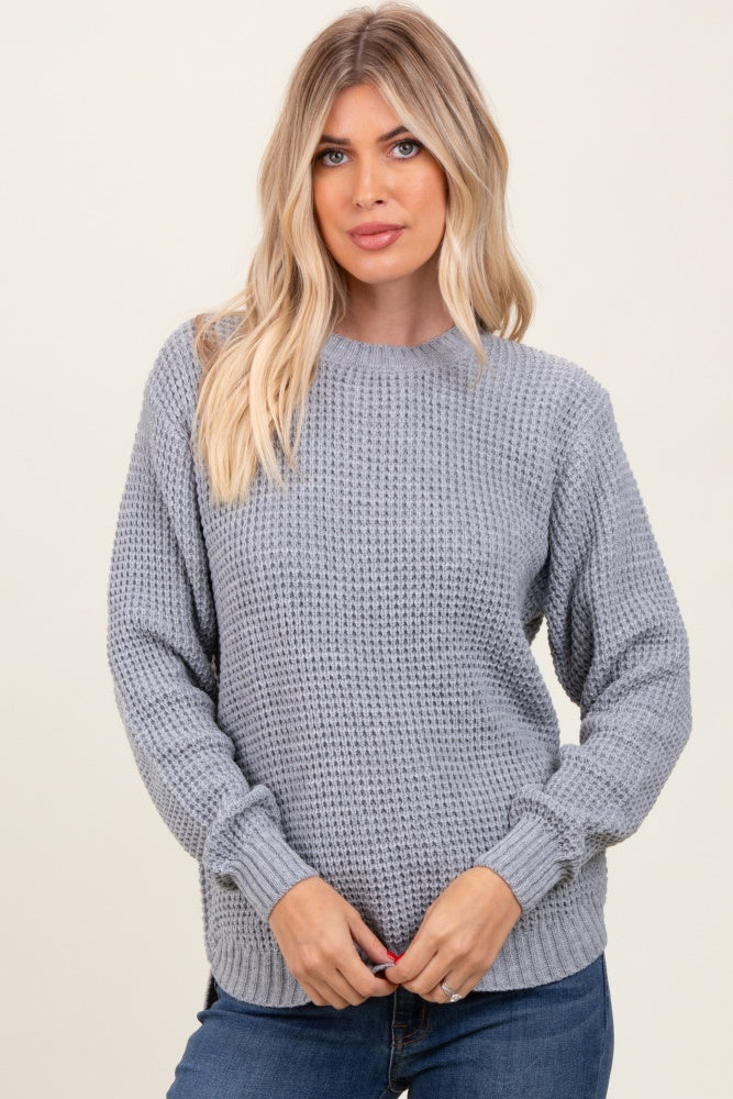 woman wearing a light gray textured knit sweater and blue jeans
