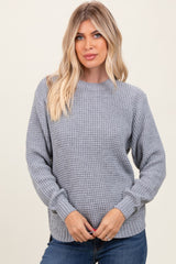 woman wearing a light gray textured knit sweater and blue jeans