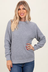 woman wearing a light gray knit sweater with a round neckline and relaxed fit, smiling with hands on her hips
