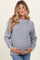 woman wearing a light grey textured maternity sweater and holding her baby bump