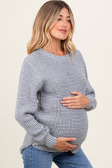 woman wearing a gray knitted maternity sweater and holding her baby bump