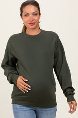 woman wearing a dark green maternity sweatshirt and holding her baby bump