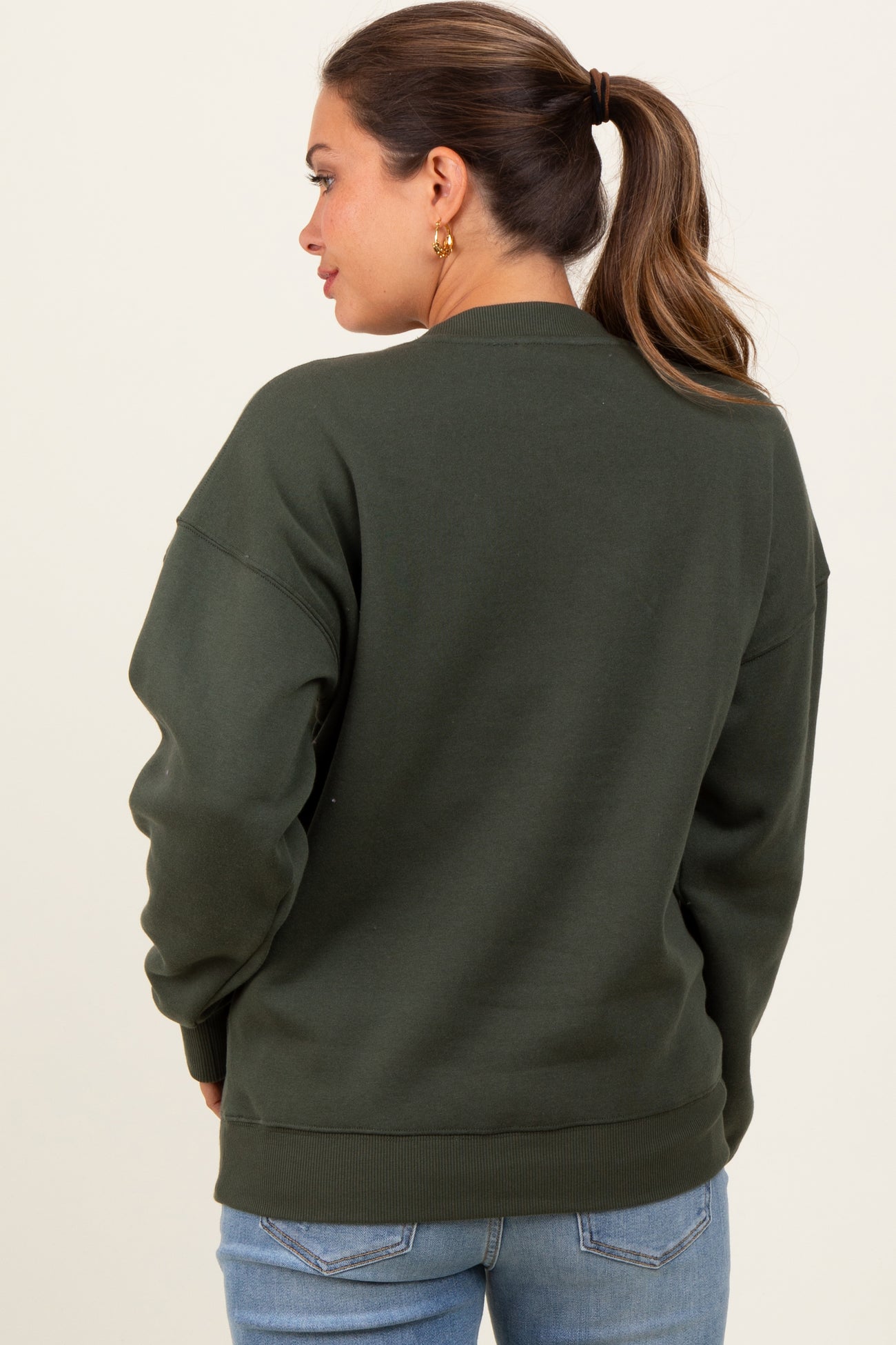 woman wearing a dark green oversized maternity sweatshirt, shown from the back with a relaxed fit