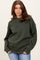 woman wearing a dark green oversized sweatshirt with ribbed cuffs and relaxed fit, paired with light blue jeans