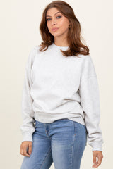 woman wearing a light gray oversized sweatshirt paired with blue jeans