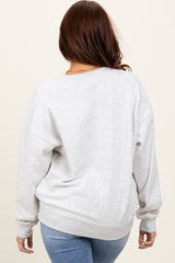 woman wearing a light gray oversized sweatshirt with a crew neckline and dropped shoulders, viewed from the back