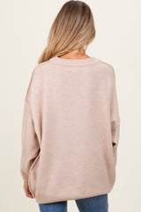 woman wearing a soft beige oversized maternity sweater, shown from the back, with relaxed fit and long sleeves