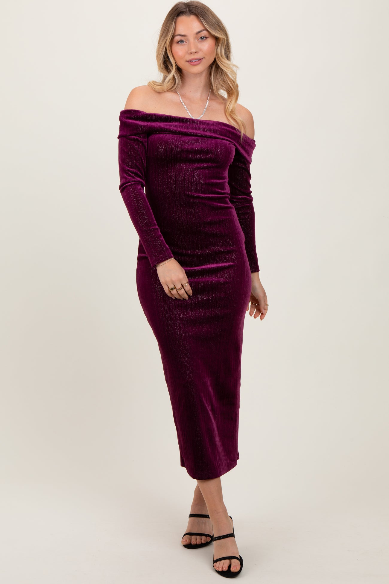 woman wearing a off-the-shoulder purple velvet midi dress with long sleeves and a fitted silhouette