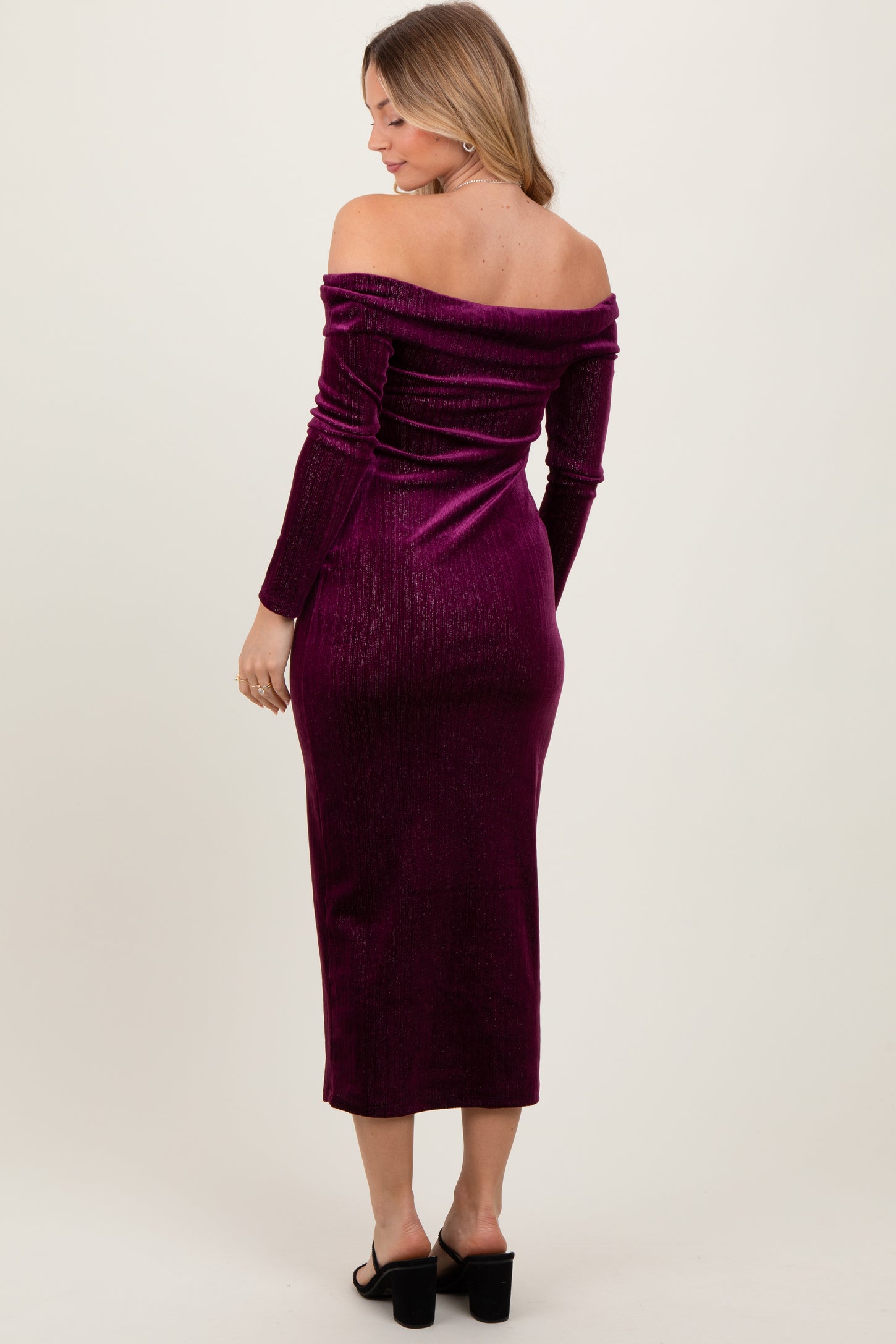 woman wearing a burgundy off-the-shoulder velvet midi dress with long sleeves and a fitted silhouette