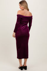 woman wearing a burgundy off-the-shoulder velvet midi dress with long sleeves and a fitted silhouette
