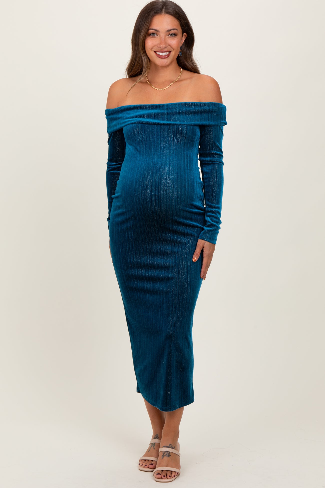 woman wearing a teal off-the-shoulder maternity dress with long sleeves and a visible baby bump