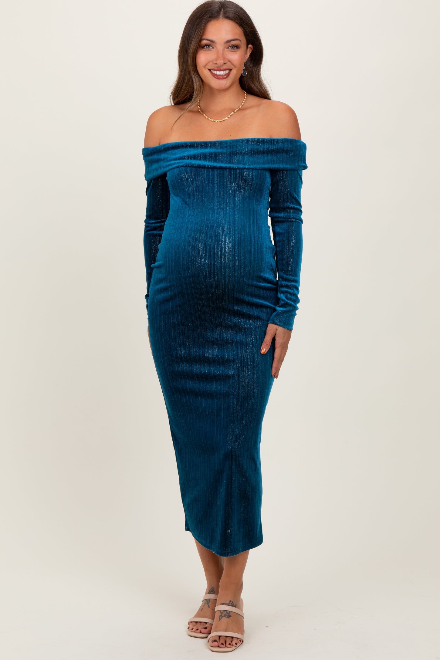 woman wearing a teal off-the-shoulder maternity dress with long sleeves and a visible baby bump