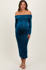 woman wearing a teal off-the-shoulder maternity dress with long sleeves and a visible baby bump