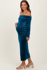 woman wearing a teal off-the-shoulder maternity dress, showcasing her baby bump, with a fitted silhouette and long sleeves