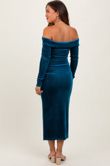woman wearing a teal off-shoulder midi maternity dress with a fitted silhouette and long sleeves
