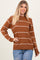 woman wearing a brown striped sweater with a crew neckline and long sleeves, paired with distressed denim jeans