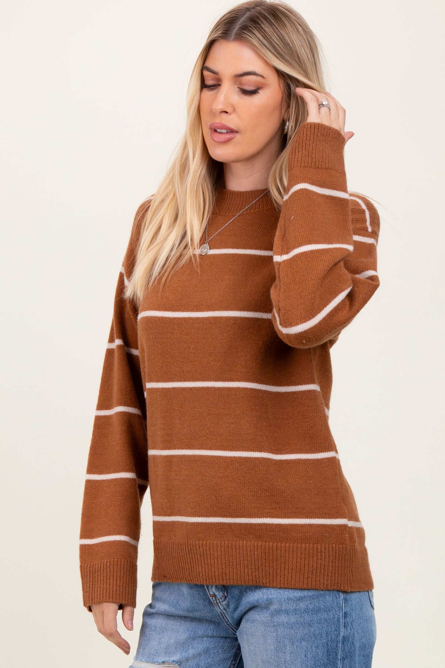 woman wearing a brown and cream striped oversized sweater with long sleeves and a relaxed fit