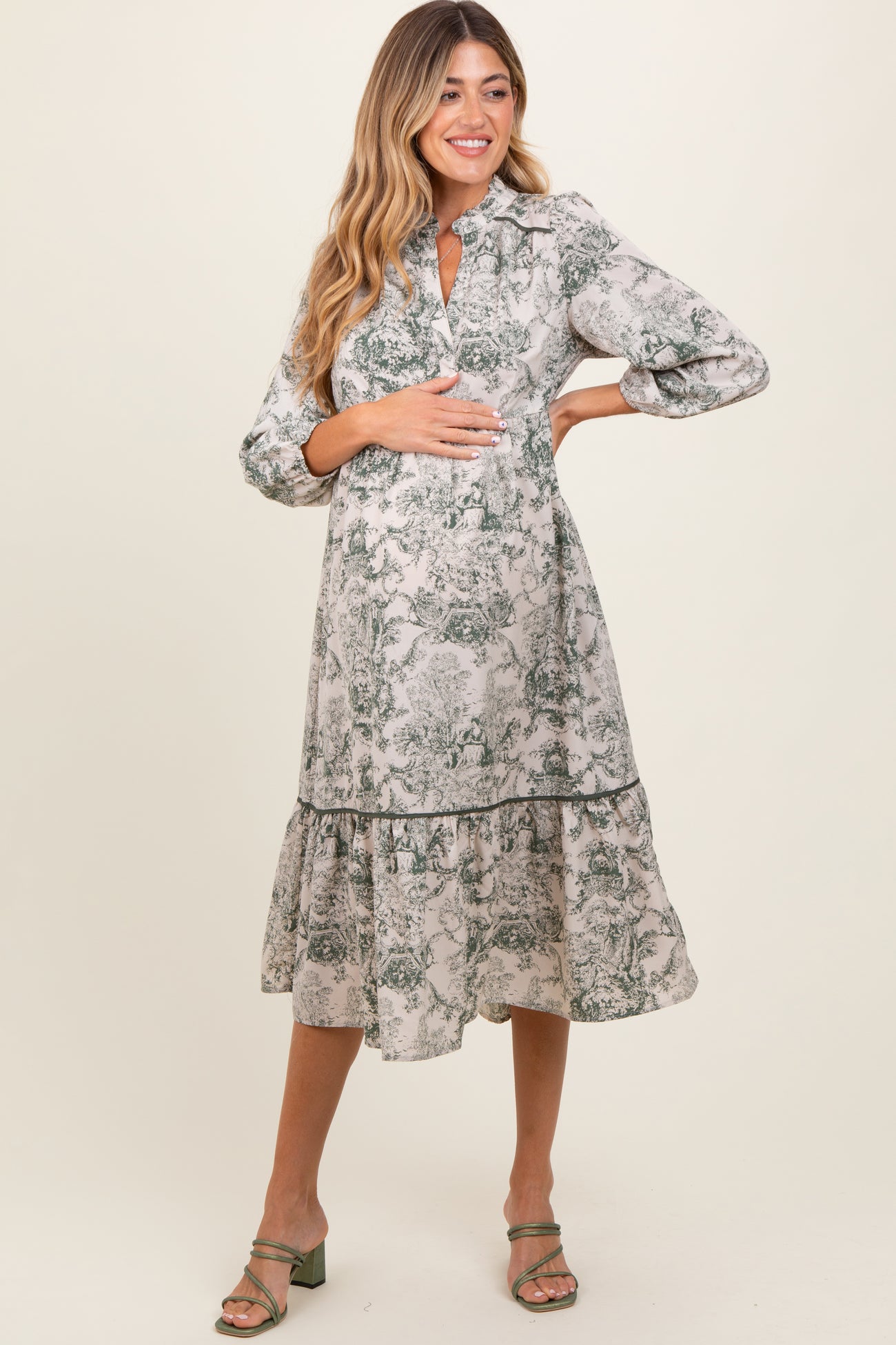 woman wearing a floral print maternity dress with a tiered skirt and a keyhole neckline, cradling her baby bump