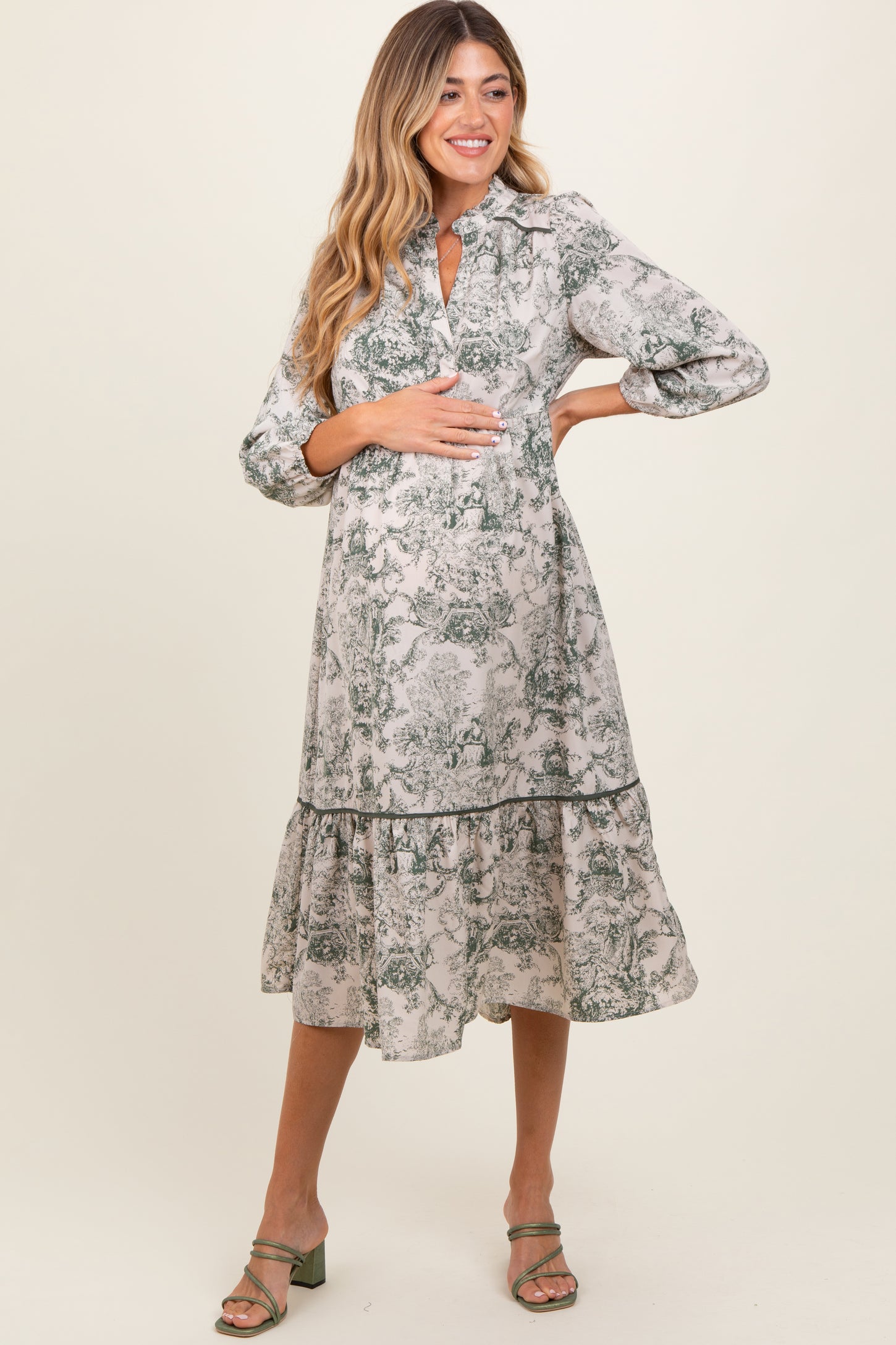 woman wearing a floral print maternity dress with a tiered skirt and a keyhole neckline, cradling her baby bump