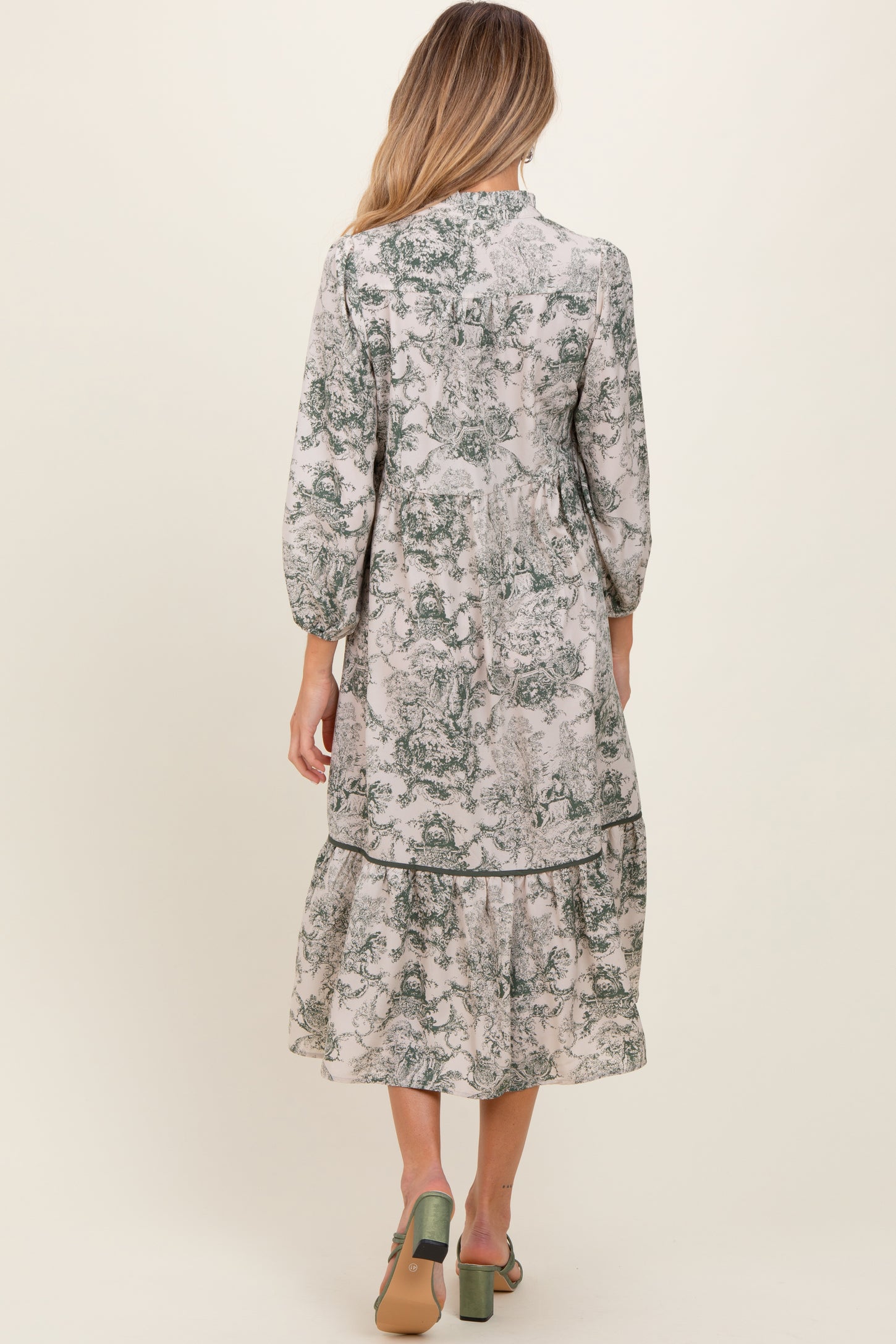 woman wearing a floral printed maternity dress with three-quarter sleeves and a tiered hem, viewed from the back