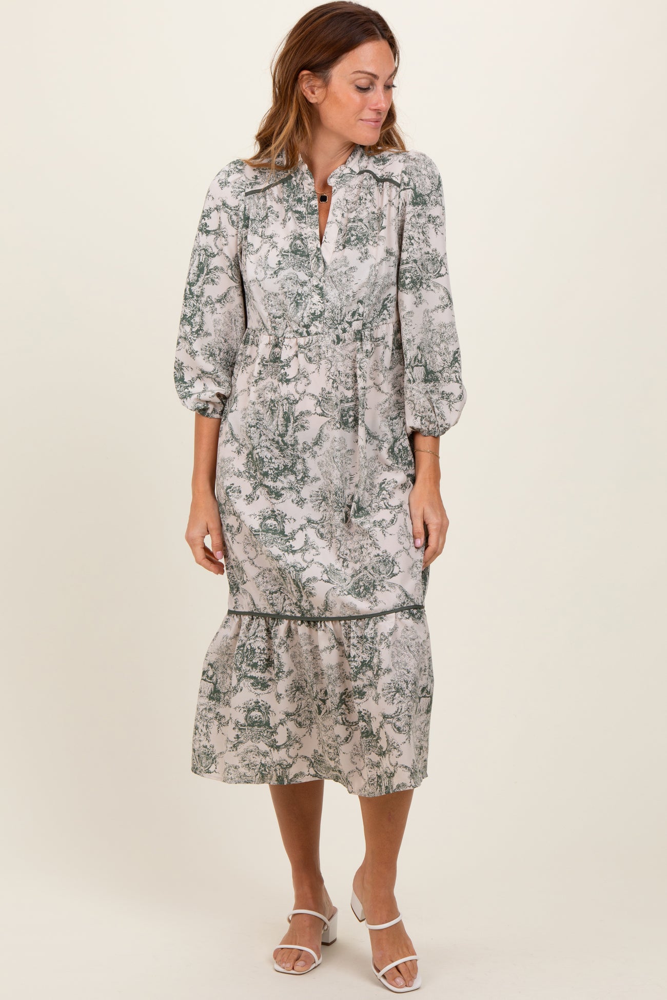 woman wearing a floral print midi dress with puff sleeves and a tiered hem, standing against a plain background