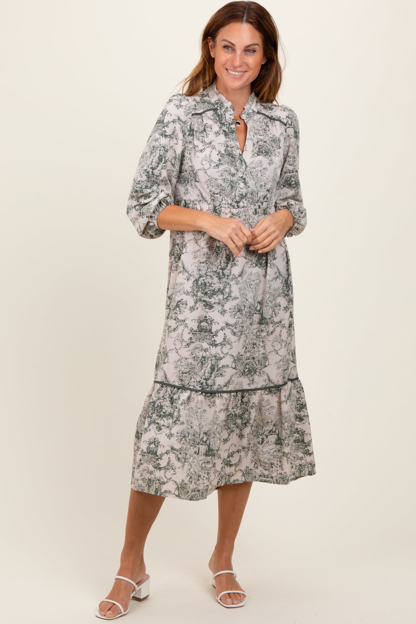 woman wearing a long-sleeve botanical print midi dress with a tiered hem and a collar, standing in a relaxed pose