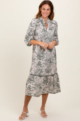 woman wearing a long-sleeve botanical print midi dress with a tiered hem and a collar, standing in a relaxed pose