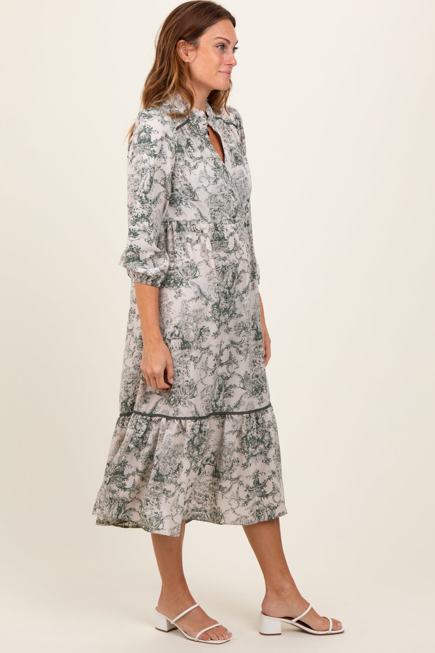 woman wearing a long sleeve green and white floral midi dress with a tiered skirt and button-up front