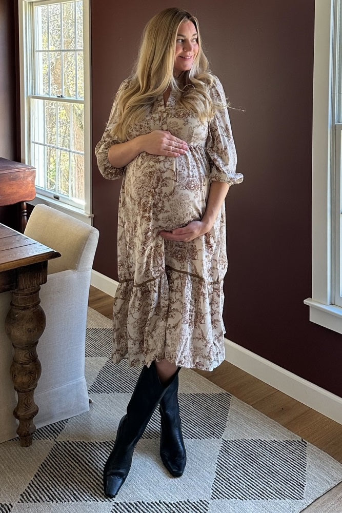 woman wearing a beige floral maternity dress with a ruffled hem and a visible baby bump